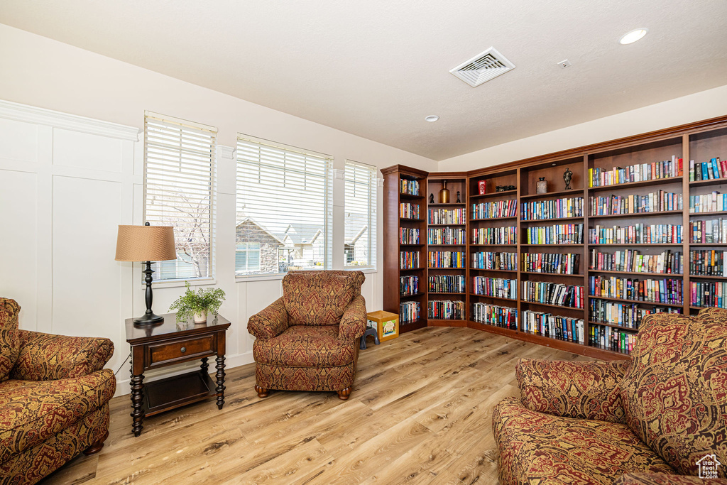 Living area with wood finished floors, recessed lighting, bookshelves, and visible vents