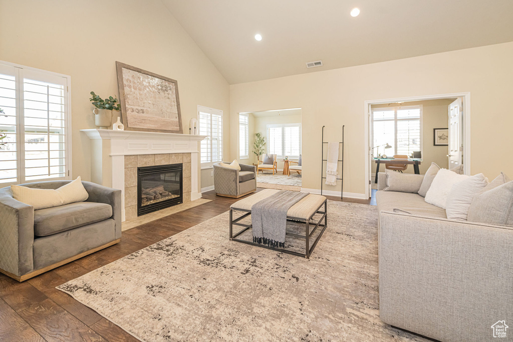 Living area featuring a fireplace, high vaulted ceiling, recessed lighting, and hardwood / wood-style flooring
