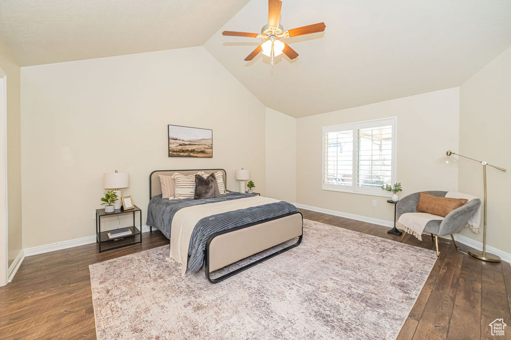 Bedroom with dark wood-style floors, vaulted ceiling, ceiling fan, and baseboards
