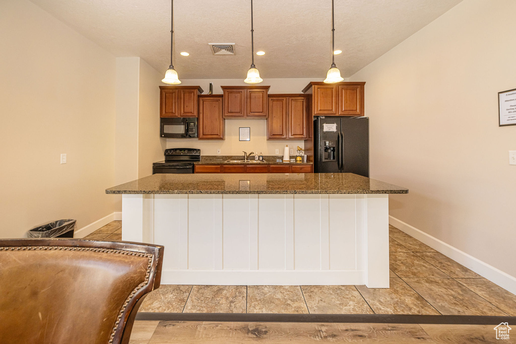 Kitchen with visible vents, brown cabinets, a kitchen island, a sink, and black appliances