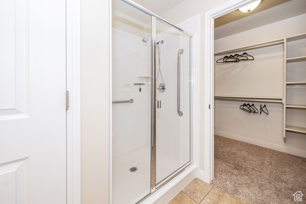 Full bathroom with baseboards, tile patterned flooring, a stall shower, and a walk in closet
