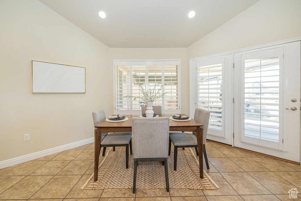 Dining space featuring light tile patterned flooring, baseboards, lofted ceiling, and recessed lighting