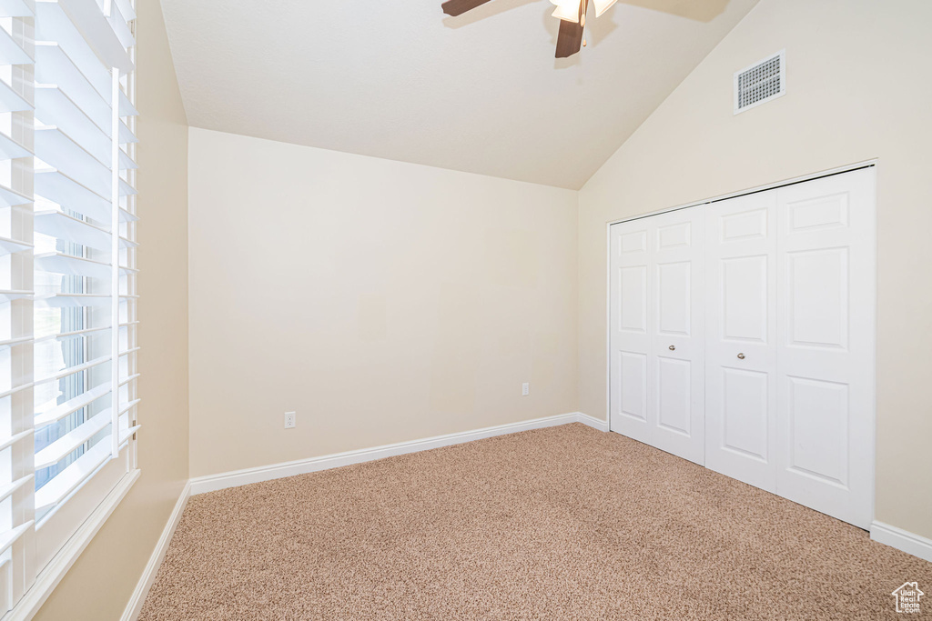 Unfurnished bedroom featuring vaulted ceiling, a closet, carpet flooring, baseboards, and visible vents