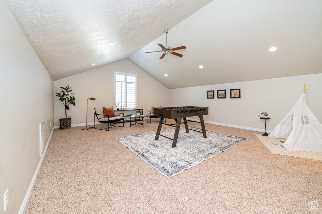 Game room featuring lofted ceiling, baseboards, a textured ceiling, ceiling fan, and light carpet