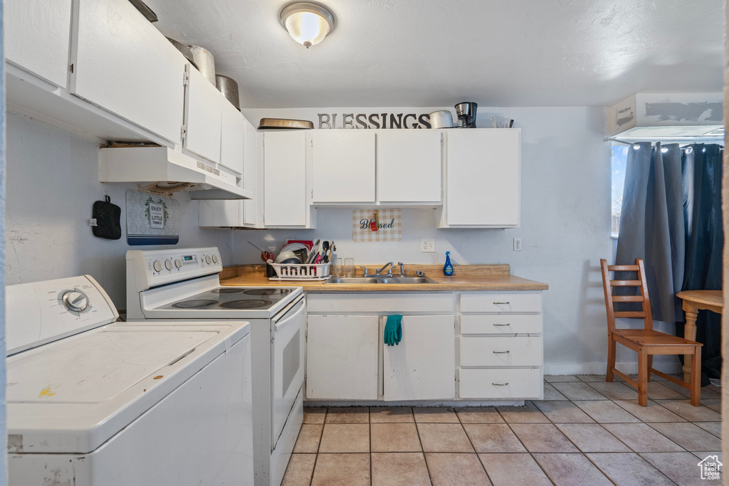 Kitchen featuring light countertops, under cabinet range hood, white cabinetry, a sink, and separate washer and dryer