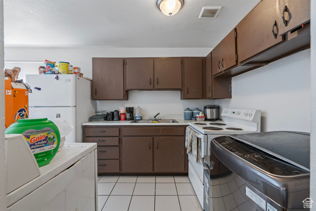 Kitchen featuring light countertops, visible vents, white appliances, washer / clothes dryer, and a sink