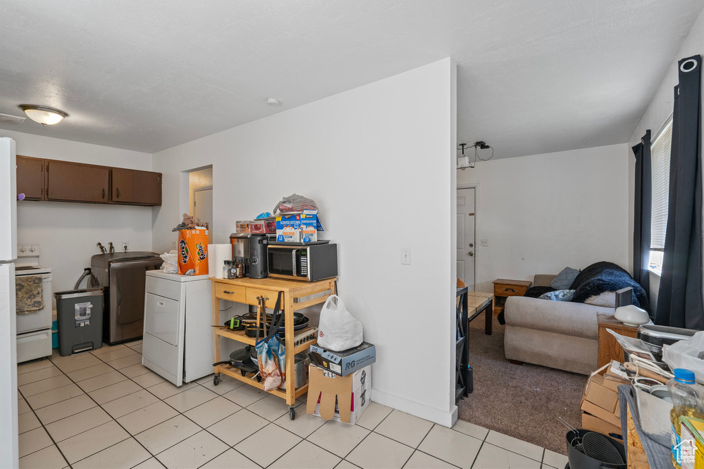 Kitchen with open floor plan, washer and dryer, white electric range oven, and light tile patterned floors