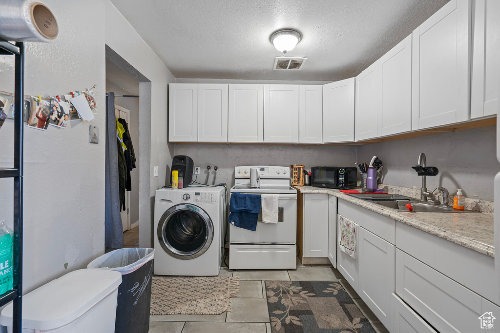 Clothes washing area featuring a sink, a textured ceiling, washer / clothes dryer, laundry area, and visible vents