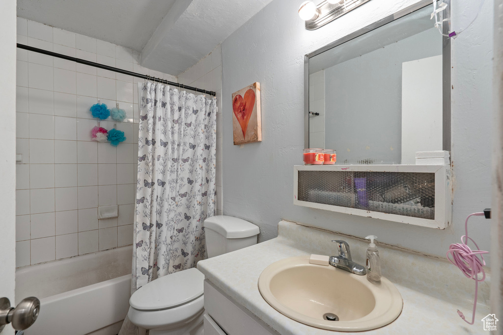 Full bathroom with toilet, shower / tub combo with curtain, and vanity