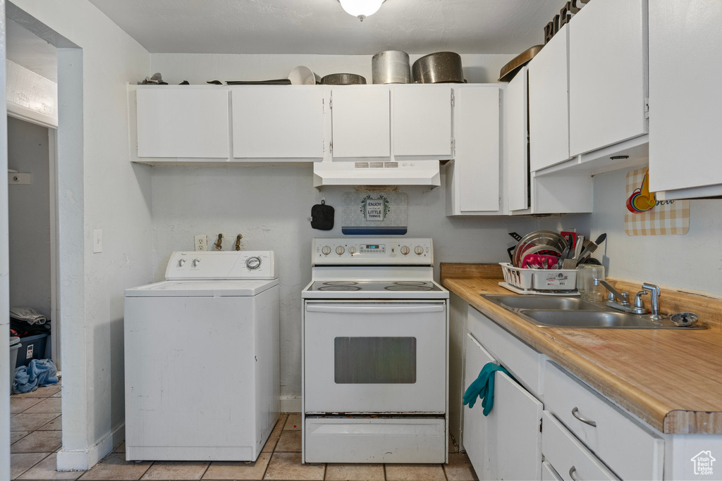 Kitchen featuring under cabinet range hood, washer / clothes dryer, a sink, white electric range, and white cabinets