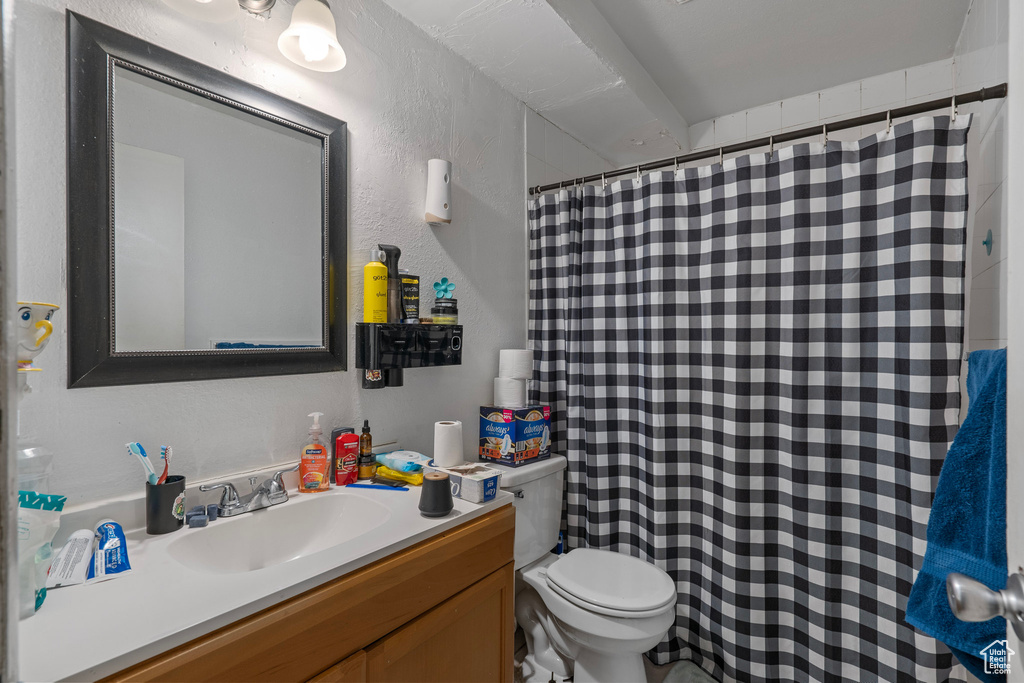 Bathroom with a textured wall, toilet, a shower with shower curtain, and vanity