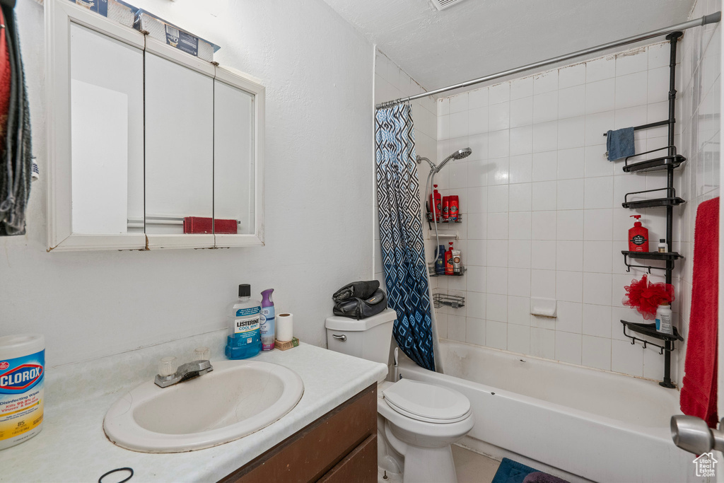 Full bath with toilet, shower / bath combo with shower curtain, and vanity