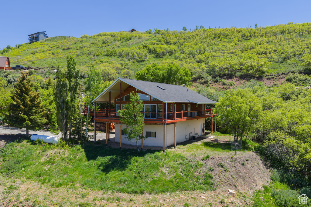 Rear view of house featuring a view of trees and a deck