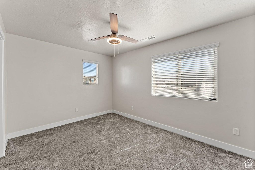 Unfurnished room with baseboards, visible vents, ceiling fan, and carpet