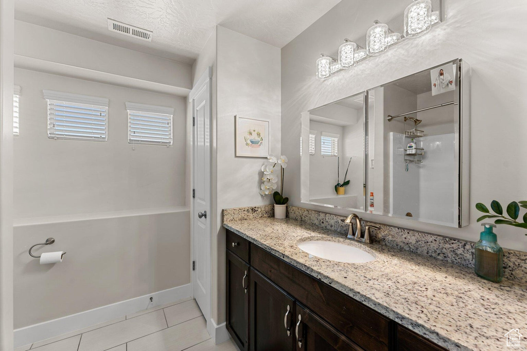 Full bathroom with vanity, baseboards, a textured ceiling, tile patterned floors, and visible vents