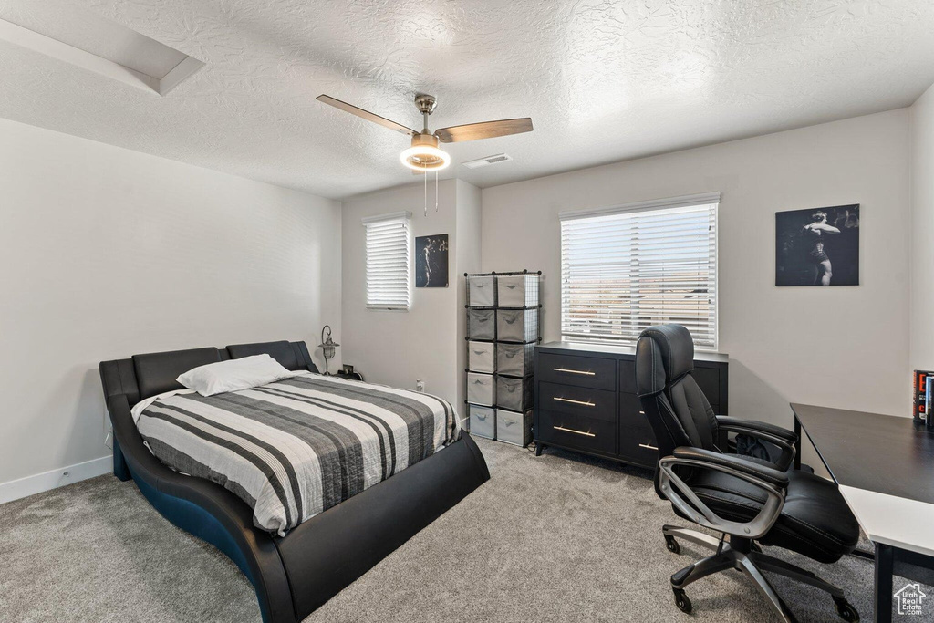 Bedroom featuring light carpet, multiple windows, visible vents, and ceiling fan