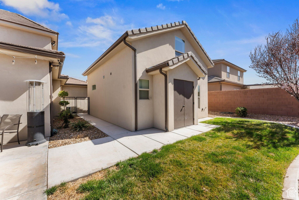 Rear view of property with stucco siding, an outbuilding, fence, and a yard