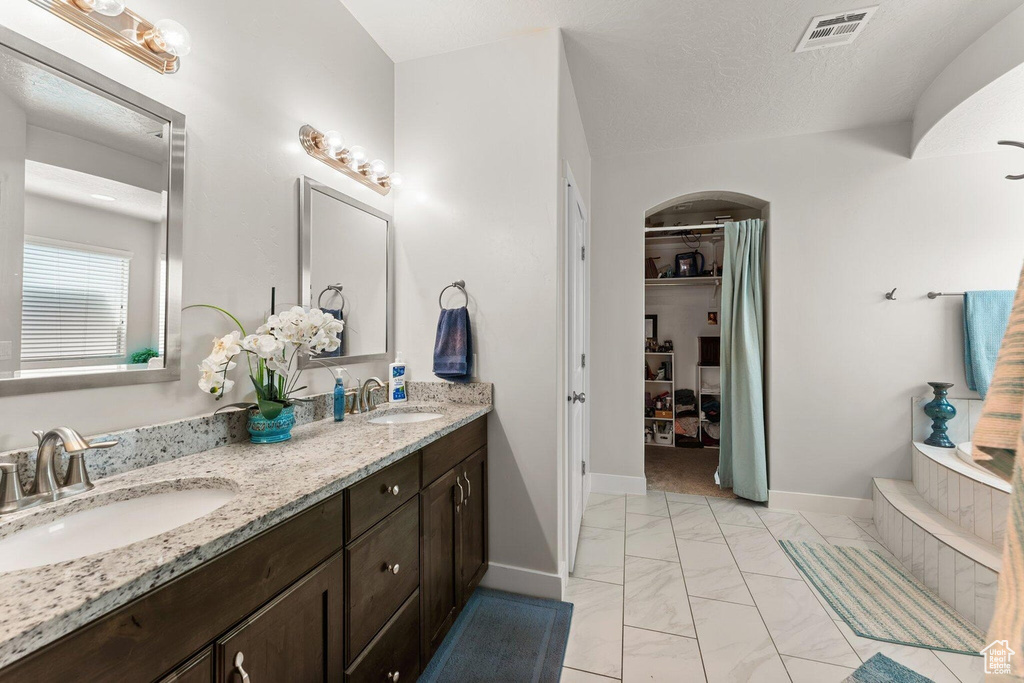 Full bathroom with marble finish floor, a sink, double vanity, and visible vents