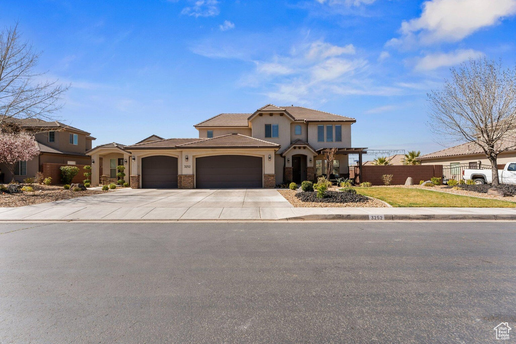 Mediterranean / spanish-style house with stone siding, fence, a garage, stucco siding, and driveway