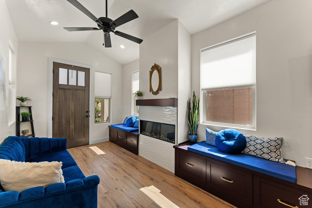 Living area with vaulted ceiling, recessed lighting, light wood finished floors, ceiling fan, and a fireplace