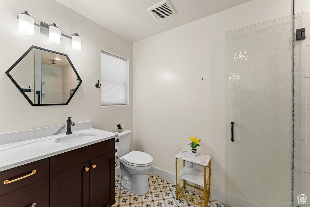 Bathroom with toilet, vanity, a shower stall, baseboards, and visible vents