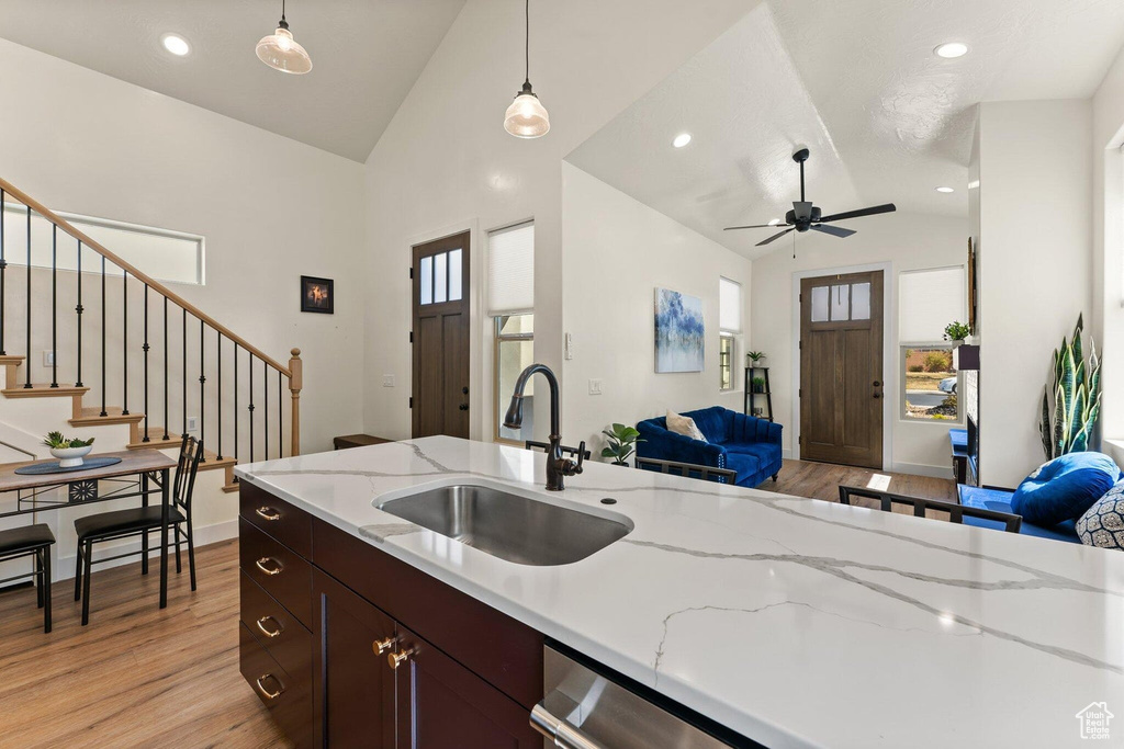 Kitchen with light wood-style flooring, lofted ceiling, a sink, open floor plan, and hanging light fixtures