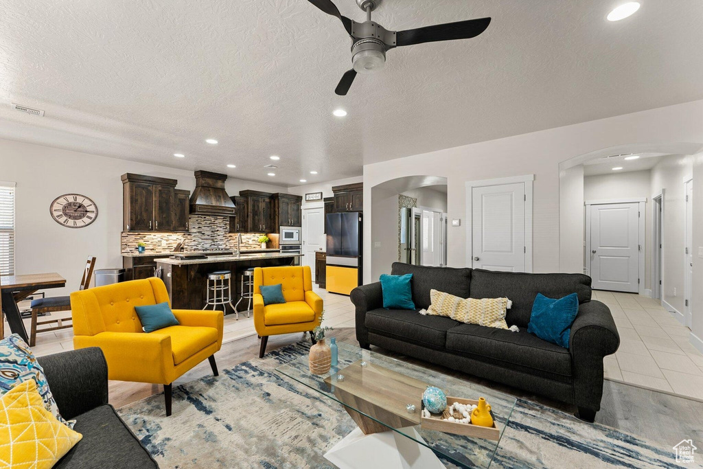 Living room featuring recessed lighting, a textured ceiling, arched walkways, visible vents, and a ceiling fan