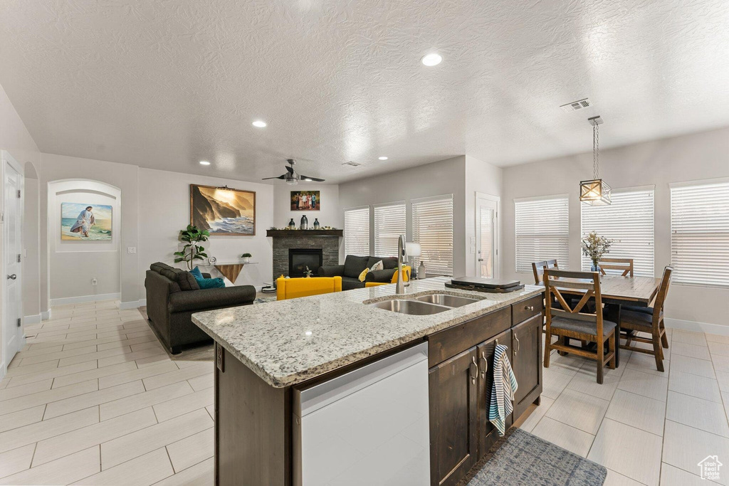 Kitchen featuring dark brown cabinetry, a sink, a fireplace, dishwasher, and ceiling fan