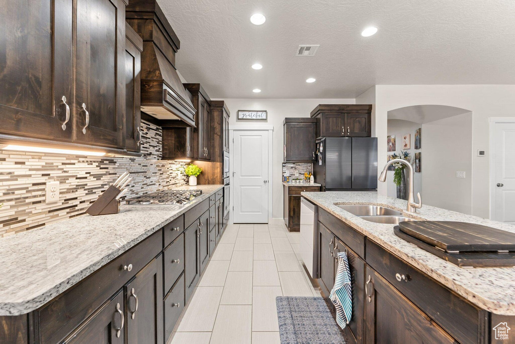 Kitchen featuring visible vents, dark brown cabinets, appliances with stainless steel finishes, arched walkways, and a sink