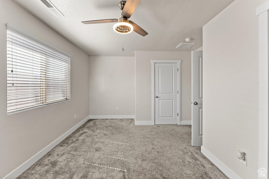 Unfurnished bedroom with a textured ceiling, visible vents, baseboards, ceiling fan, and carpet floors