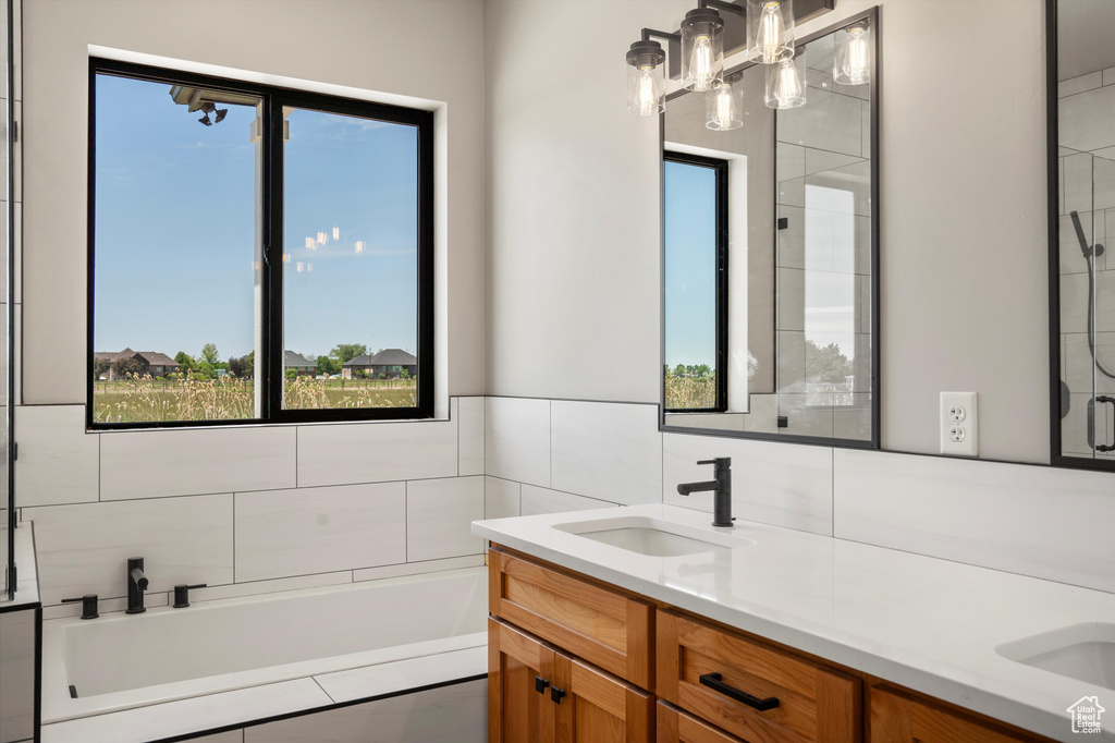 Bathroom featuring double vanity, plenty of natural light, and a bath