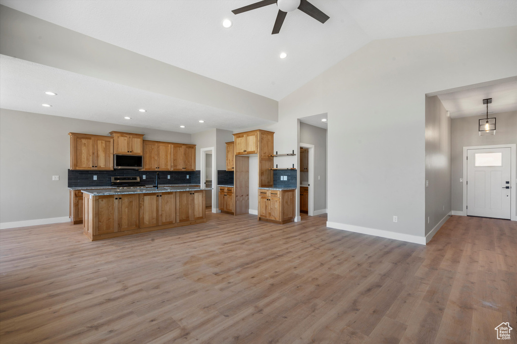 Kitchen with stainless steel appliances, open floor plan, a ceiling fan, backsplash, and recessed lighting