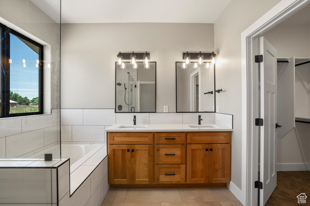 Bathroom with double vanity, a bath, a tile shower, and tile patterned floors