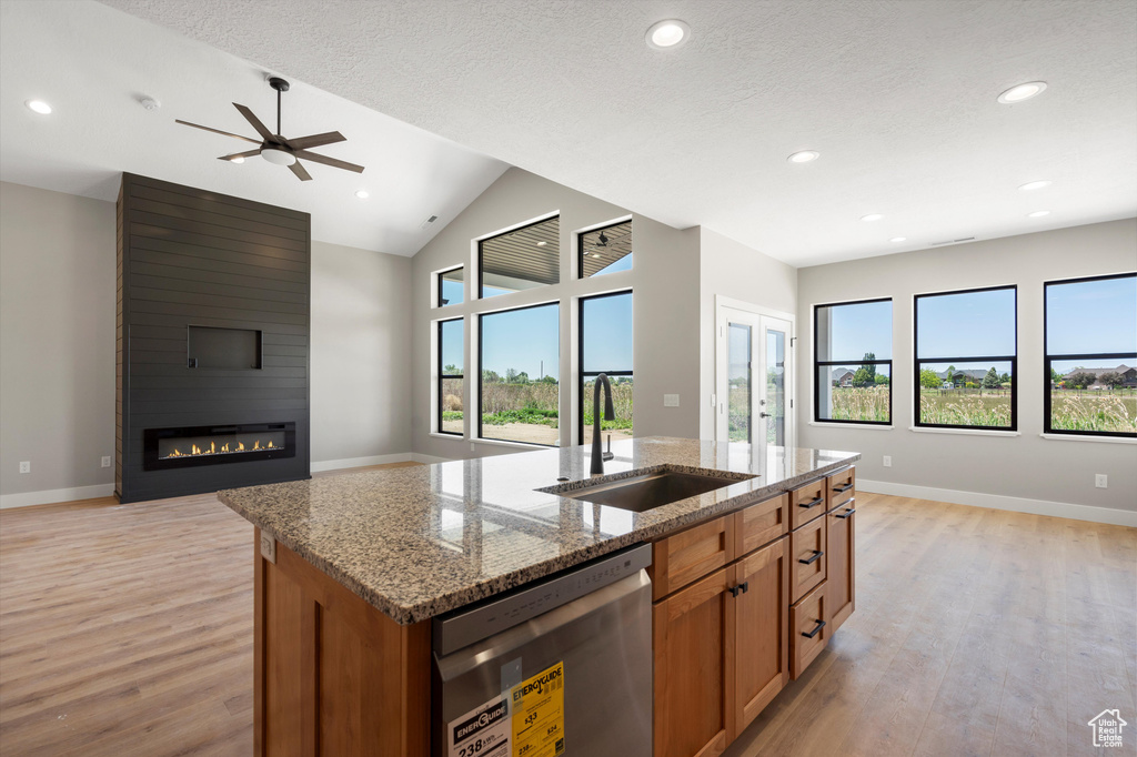 Kitchen with open floor plan, dishwasher, a sink, light wood finished floors, and recessed lighting