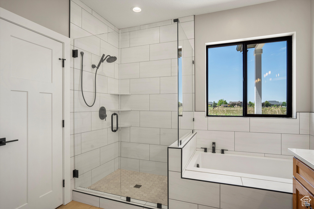 Bathroom with a shower stall, a garden tub, healthy amount of natural light, vanity, and recessed lighting