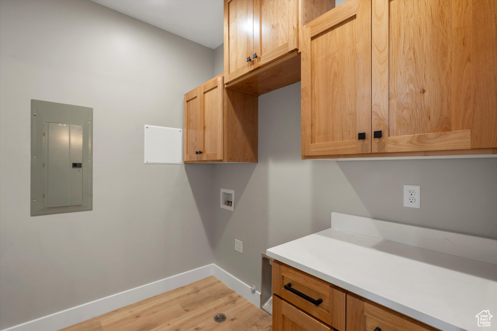 Laundry room featuring electric panel, cabinet space, hookup for a washing machine, baseboards, and light wood finished floors