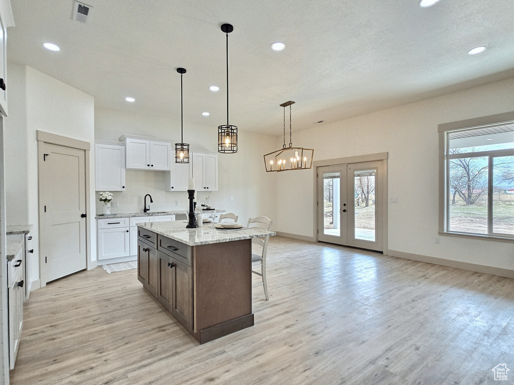 Kitchen with baseboards, white cabinetry, light wood-type flooring, a breakfast bar area, and a center island