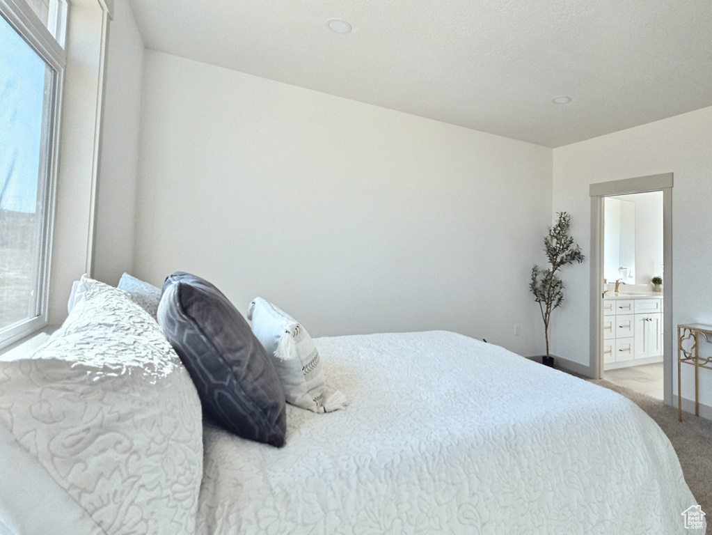 Bedroom with light carpet, baseboards, and ensuite bath