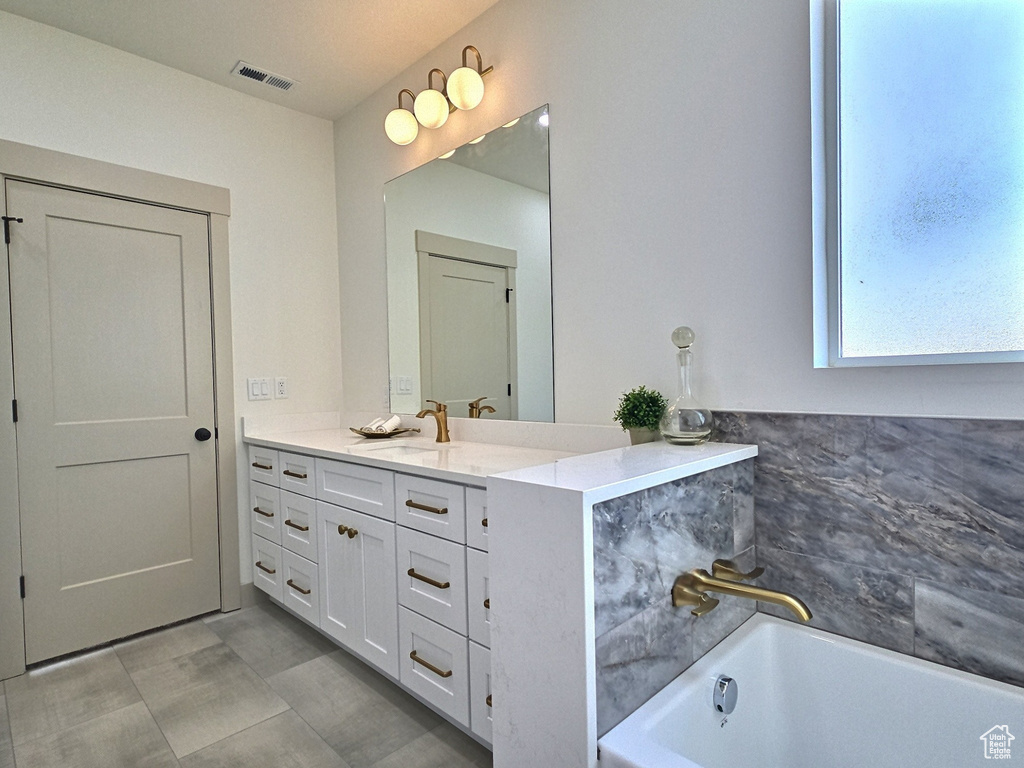 Full bathroom with a tub, visible vents, and vanity
