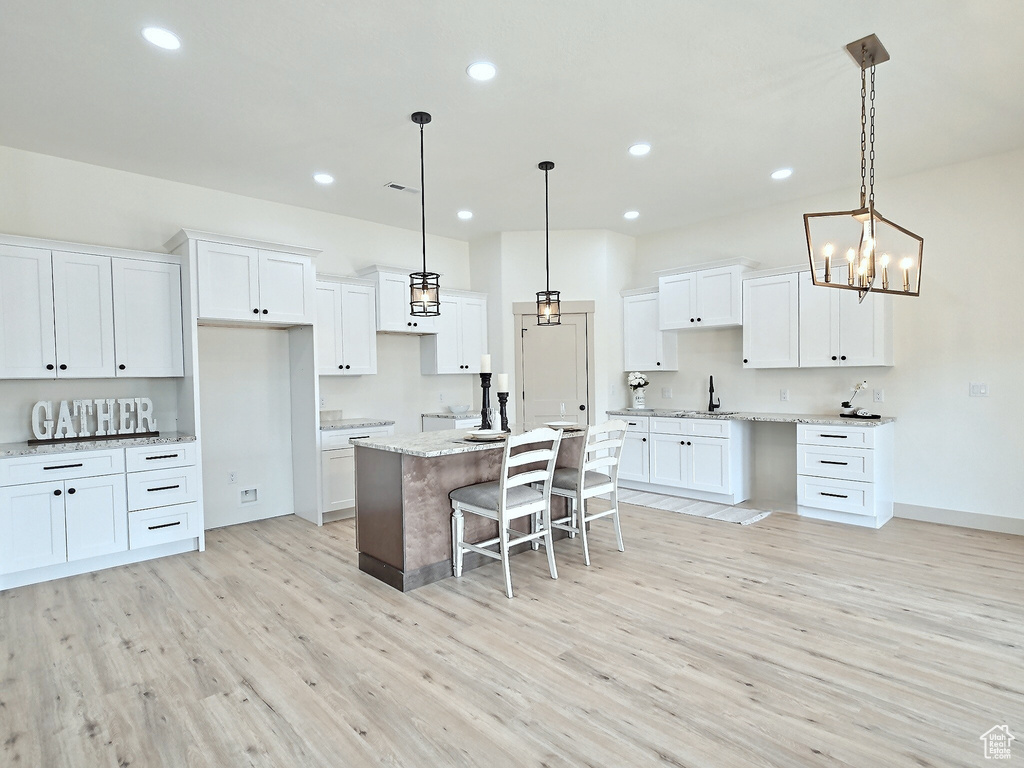 Kitchen featuring a sink, light wood finished floors, a center island, white cabinets, and recessed lighting