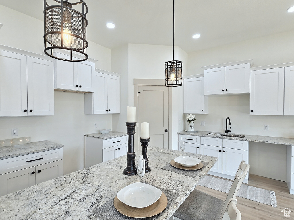 Kitchen with white cabinetry, a sink, and light stone counters
