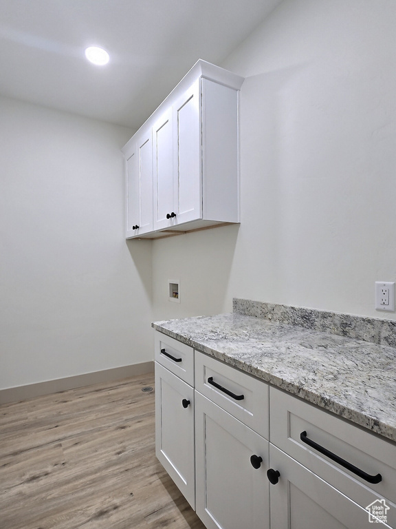 Laundry room with washer hookup, cabinet space, light wood-style flooring, and baseboards