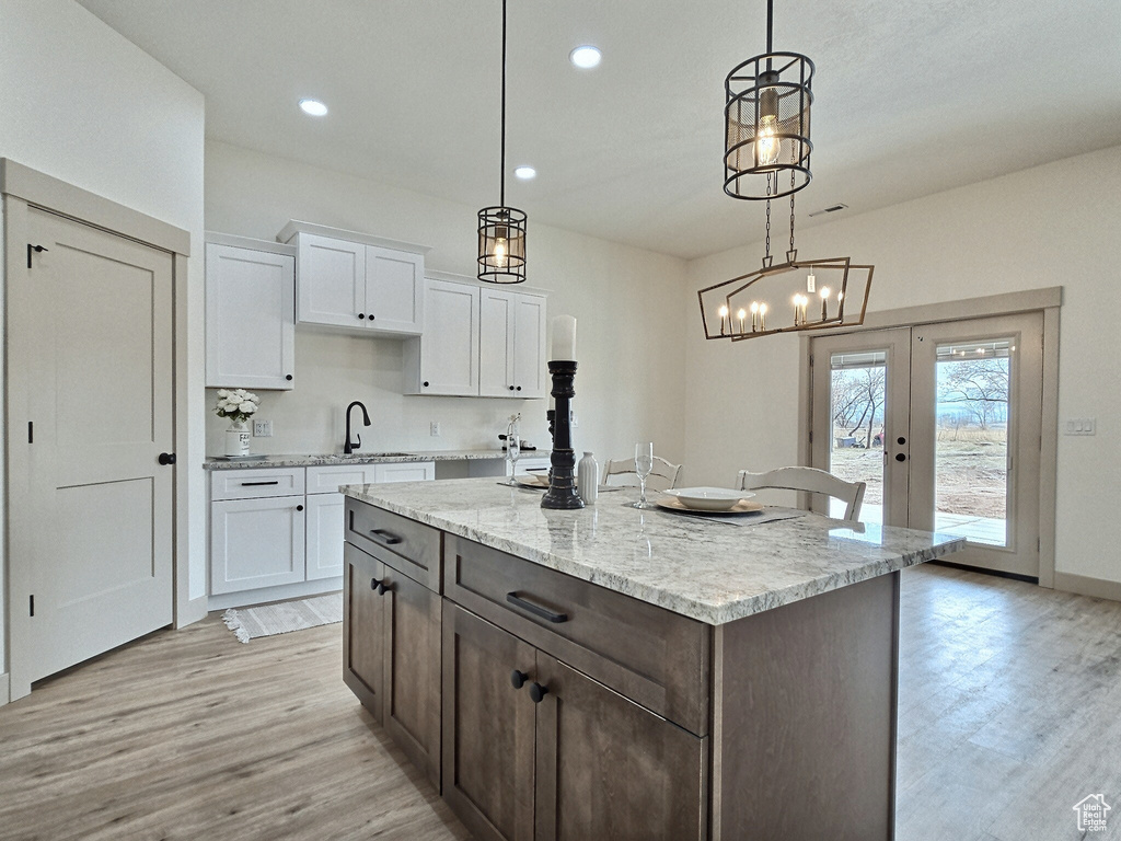 Kitchen with white cabinetry, a sink, french doors, and light wood-type flooring