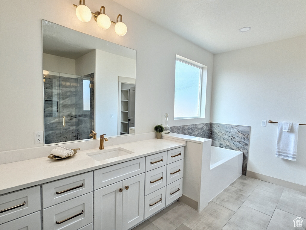 Full bath featuring tile patterned flooring, vanity, baseboards, a stall shower, and a garden tub