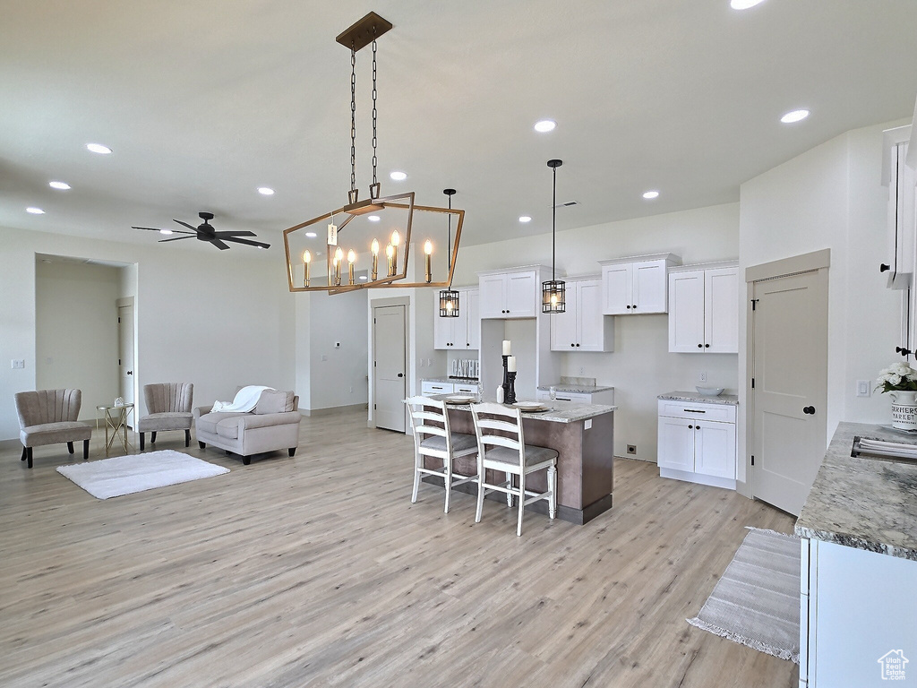 Kitchen with light wood finished floors, open floor plan, white cabinetry, and recessed lighting
