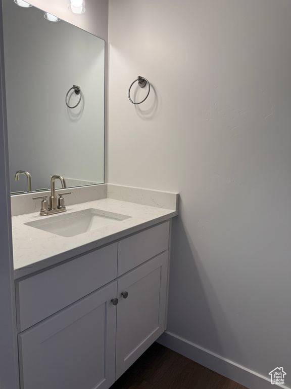 Bathroom featuring vanity, wood finished floors, and baseboards