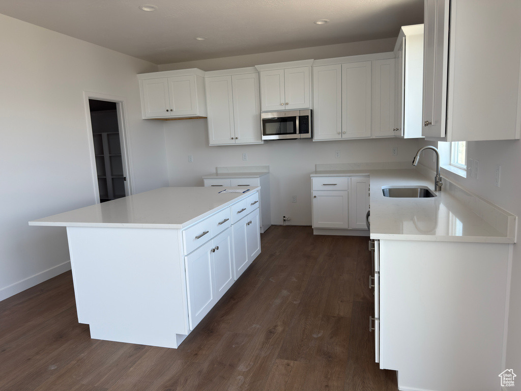 Kitchen with a sink, stainless steel microwave, dark wood-style floors, white cabinets, and recessed lighting