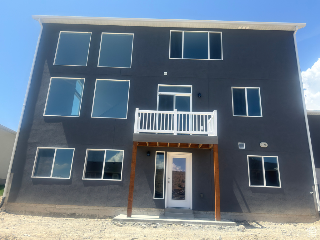 Back of property with a balcony and stucco siding