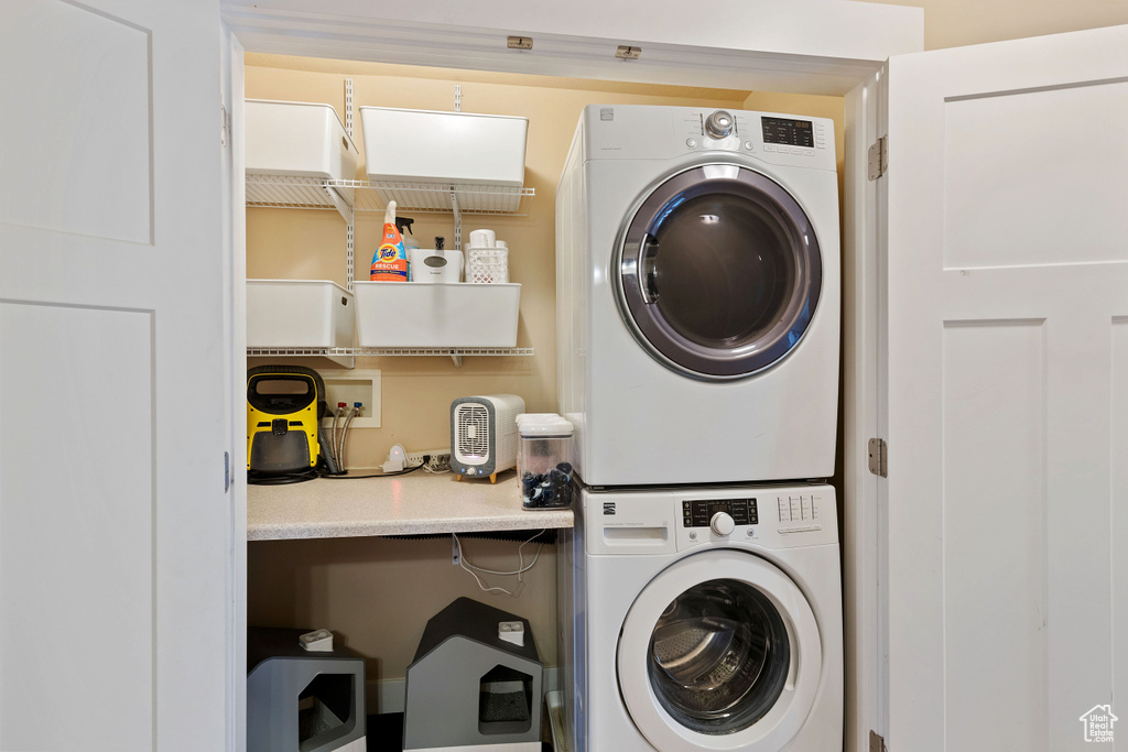 Clothes washing area featuring stacked washer and dryer and laundry area