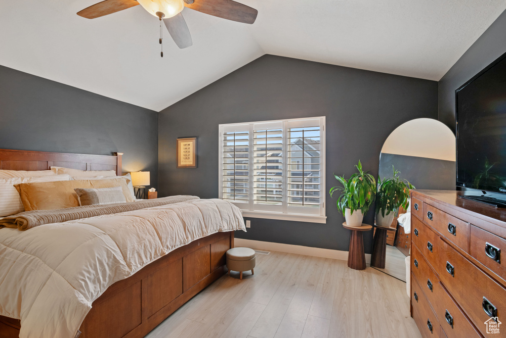 Bedroom with light wood-style flooring, baseboards, vaulted ceiling, and ceiling fan